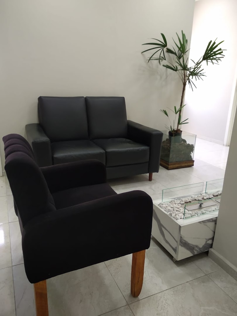 Recanto da recepção com sofás pretos e mesa de centro em mármore